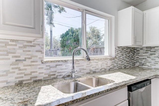 kitchen with dishwasher, light stone counters, white cabinetry, and sink