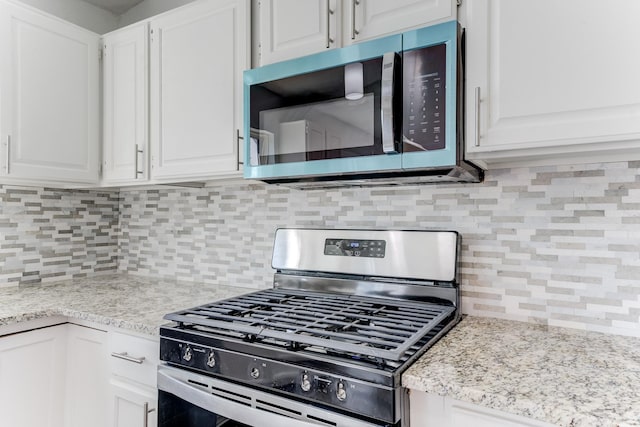 kitchen with light stone counters, white cabinetry, appliances with stainless steel finishes, and tasteful backsplash