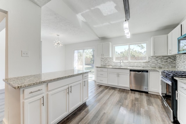 kitchen with pendant lighting, white cabinetry, and appliances with stainless steel finishes