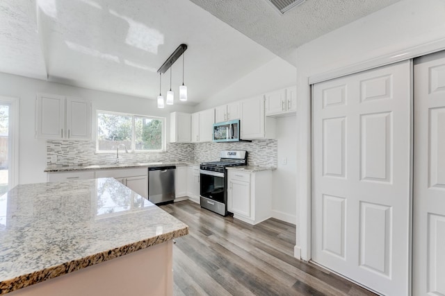 kitchen featuring decorative light fixtures, stainless steel appliances, white cabinetry, and a wealth of natural light