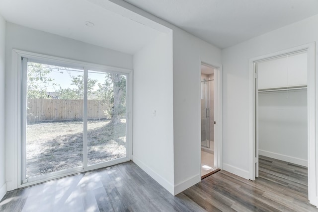 unfurnished bedroom with access to exterior, a closet, ensuite bath, and dark hardwood / wood-style floors