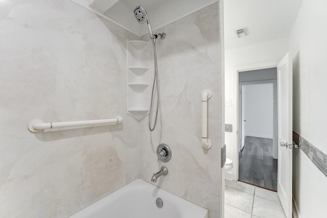 bathroom with tile patterned flooring, toilet, and tiled shower / bath