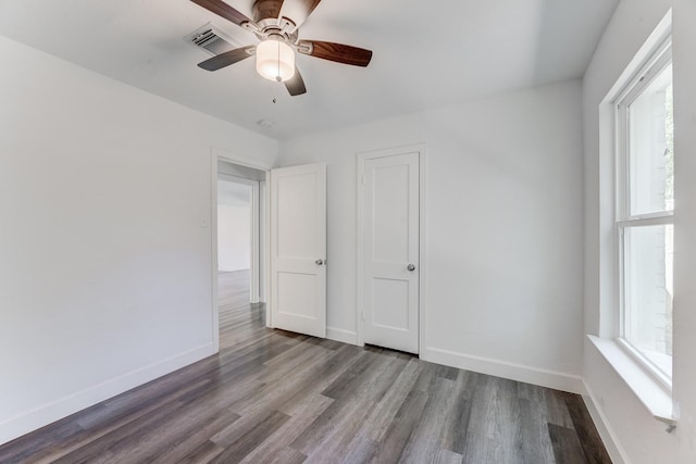 unfurnished bedroom with hardwood / wood-style flooring, ceiling fan, and multiple windows