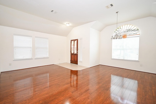 unfurnished living room with wood-type flooring, lofted ceiling, and a notable chandelier