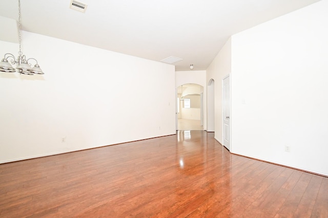 unfurnished room featuring wood-type flooring and an inviting chandelier