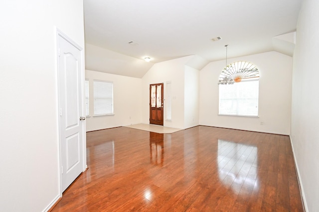 spare room with a chandelier, hardwood / wood-style flooring, and vaulted ceiling