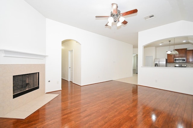 unfurnished living room with a fireplace, hardwood / wood-style flooring, ceiling fan, and lofted ceiling