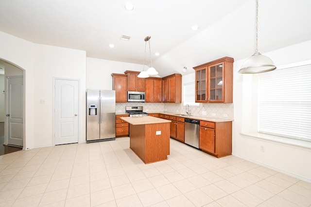 kitchen with sink, stainless steel appliances, backsplash, pendant lighting, and a kitchen island