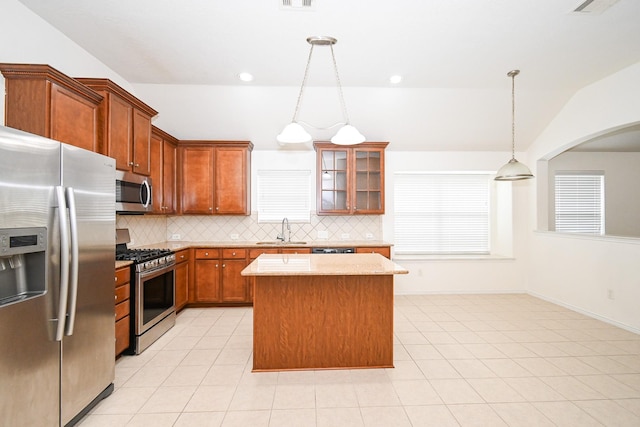 kitchen with pendant lighting, a center island, sink, appliances with stainless steel finishes, and tasteful backsplash