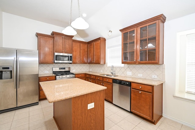 kitchen with appliances with stainless steel finishes, backsplash, sink, pendant lighting, and a kitchen island