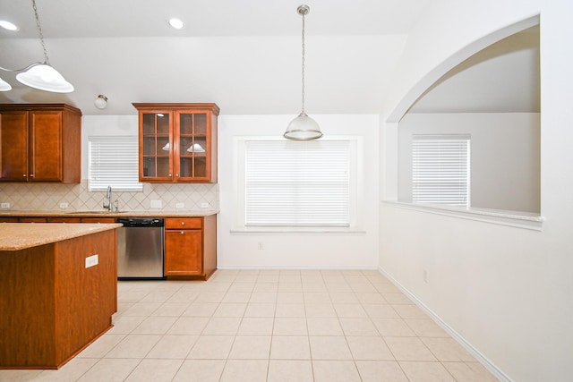 kitchen featuring light stone countertops, sink, stainless steel dishwasher, backsplash, and pendant lighting