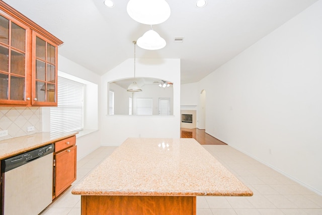 kitchen with hanging light fixtures, stainless steel dishwasher, ceiling fan, decorative backsplash, and a kitchen island