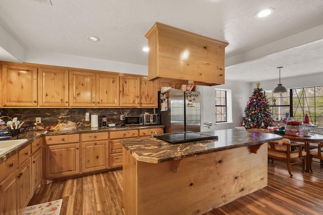 kitchen with pendant lighting, a center island, stainless steel refrigerator, and a breakfast bar area