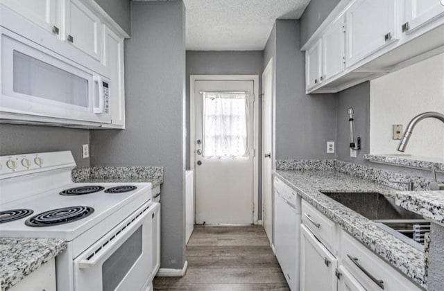 kitchen featuring white appliances, a textured ceiling, sink, wood-type flooring, and white cabinets