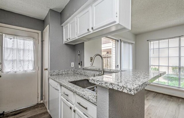 kitchen with kitchen peninsula, dark hardwood / wood-style floors, white cabinetry, and dishwasher