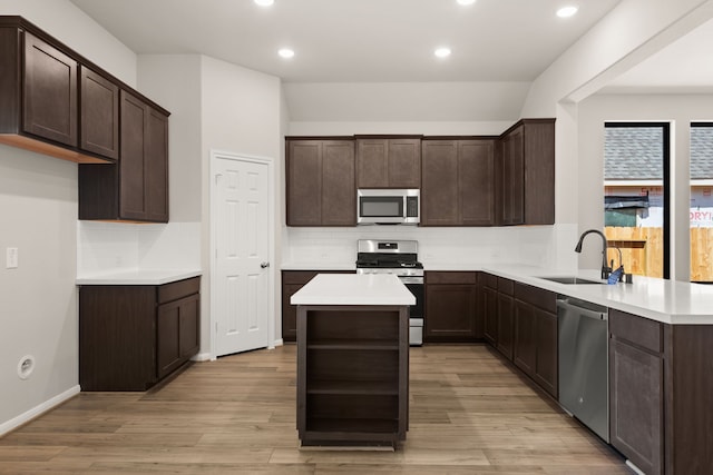 kitchen featuring dark brown cabinetry, sink, light wood-type flooring, and appliances with stainless steel finishes