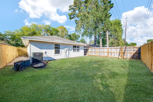 rear view of property featuring central AC unit and a lawn