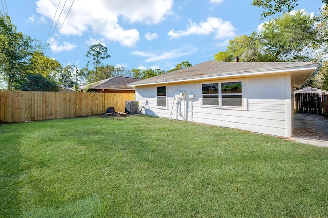 rear view of property featuring a yard and central AC unit