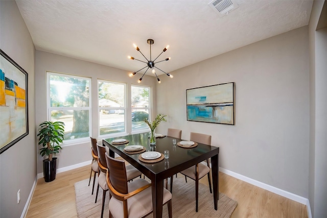 dining space featuring a chandelier, a textured ceiling, and light hardwood / wood-style flooring