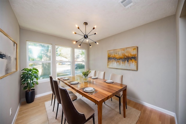 dining area featuring a textured ceiling, light wood-type flooring, and an inviting chandelier