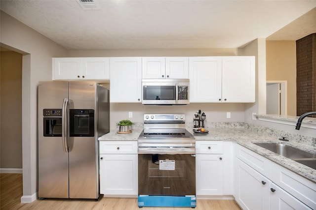 kitchen featuring white cabinets, sink, stainless steel appliances, and light hardwood / wood-style flooring