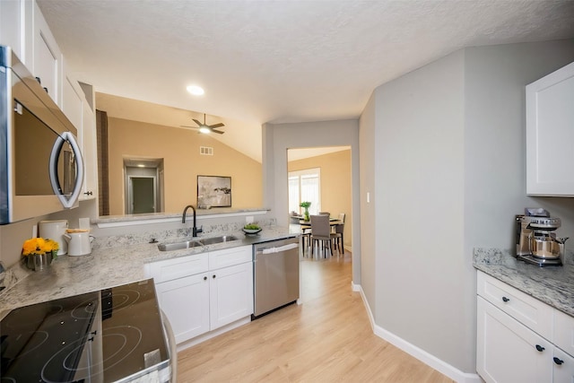 kitchen featuring sink, vaulted ceiling, light wood-type flooring, appliances with stainless steel finishes, and white cabinetry