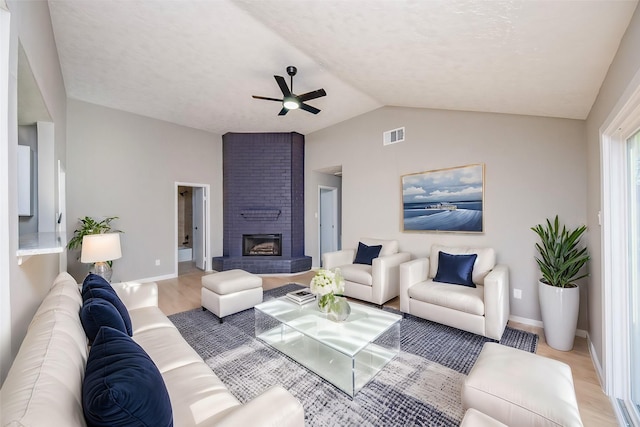 living room featuring a brick fireplace, ceiling fan, wood-type flooring, and vaulted ceiling