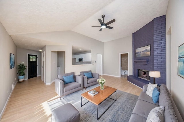 living room featuring a fireplace, light wood-type flooring, vaulted ceiling, and ceiling fan