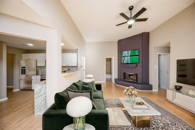 living room with ceiling fan, a fireplace, and light wood-type flooring