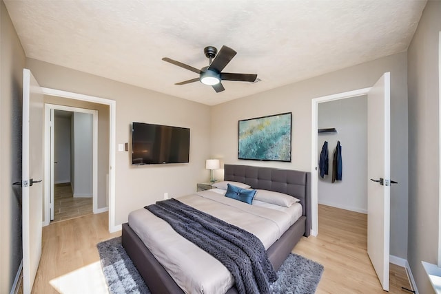 bedroom with ceiling fan, light hardwood / wood-style floors, and a textured ceiling