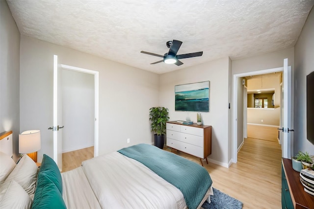 bedroom with a textured ceiling, light wood-type flooring, and ceiling fan