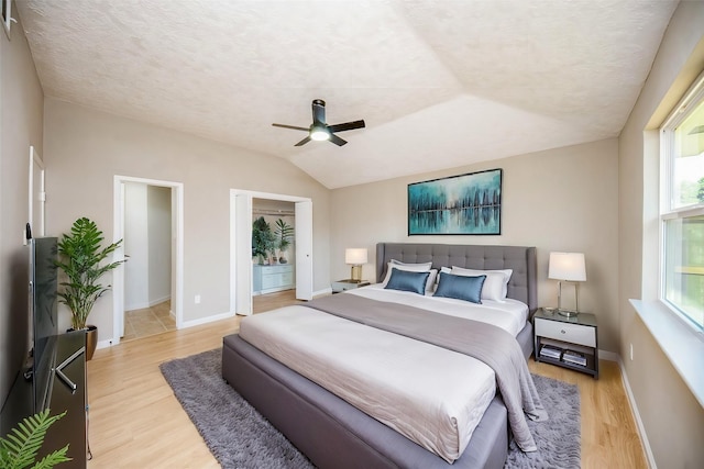 bedroom featuring a textured ceiling, ceiling fan, light hardwood / wood-style floors, and vaulted ceiling