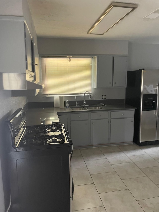 kitchen with range with gas stovetop, stainless steel fridge, light tile patterned floors, and sink