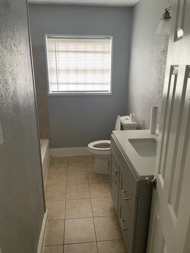 bathroom with tile patterned floors, a wealth of natural light, vanity, and toilet