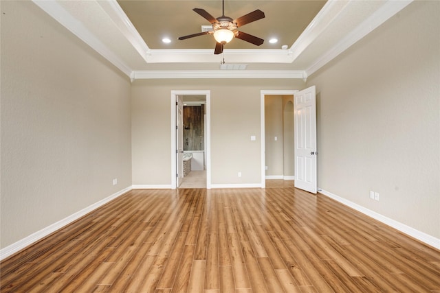 unfurnished bedroom featuring light hardwood / wood-style floors, a tray ceiling, and ornamental molding