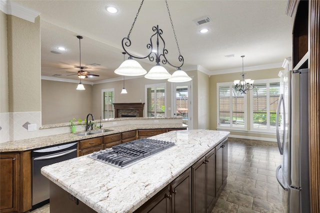 kitchen featuring light stone counters, ceiling fan with notable chandelier, stainless steel appliances, sink, and a kitchen island