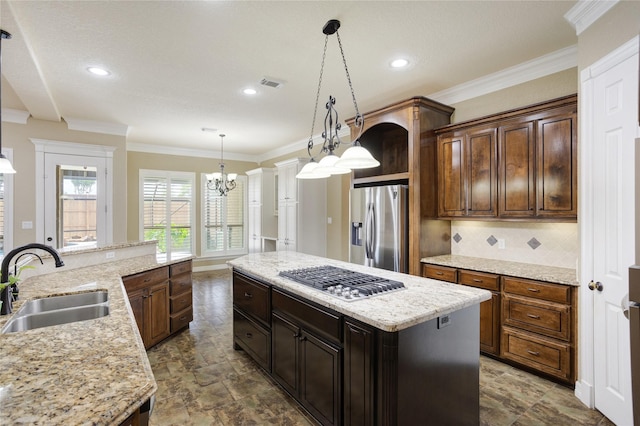 kitchen featuring appliances with stainless steel finishes, sink, pendant lighting, a chandelier, and a center island