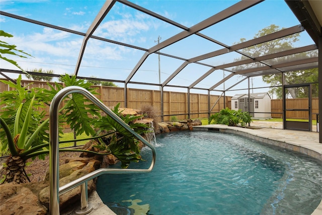 view of pool featuring glass enclosure, pool water feature, and a storage shed