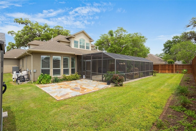 back of property with glass enclosure, a yard, and a patio