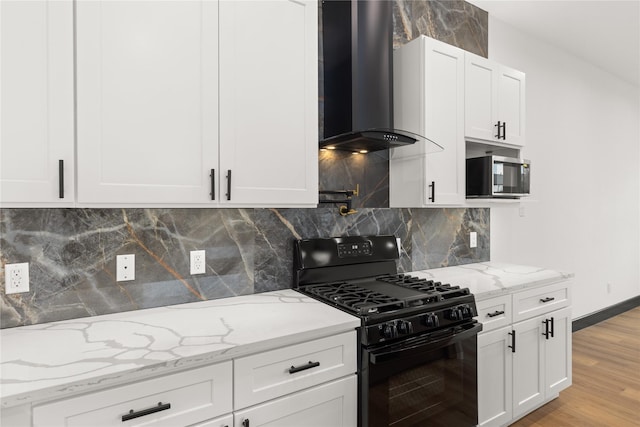 kitchen featuring white cabinetry, wall chimney exhaust hood, black gas range oven, light hardwood / wood-style flooring, and backsplash