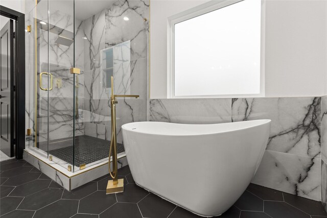 bathroom with tile patterned flooring, separate shower and tub, tile walls, and a wealth of natural light