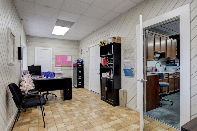 office space featuring light tile patterned floors, a drop ceiling, and wooden walls