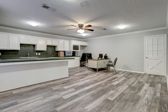 kitchen with white cabinets, light hardwood / wood-style floors, and a textured ceiling