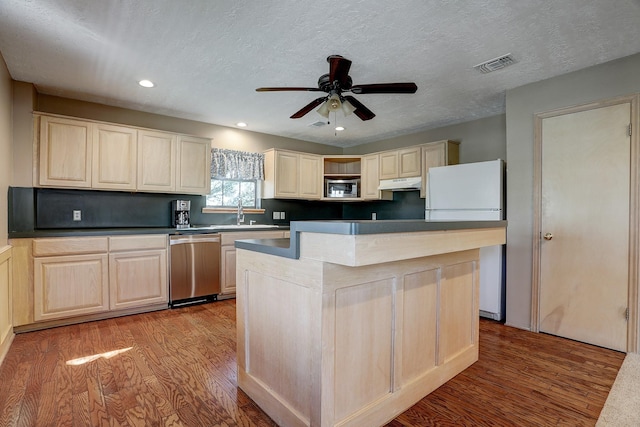 kitchen featuring ceiling fan, a center island, stainless steel appliances, a textured ceiling, and light wood-type flooring