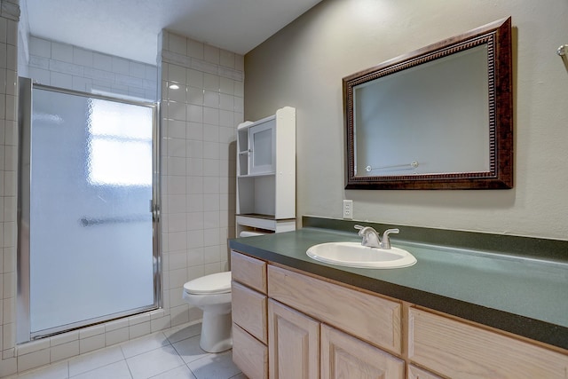 bathroom featuring tile patterned flooring, toilet, vanity, a shower with shower door, and tile walls