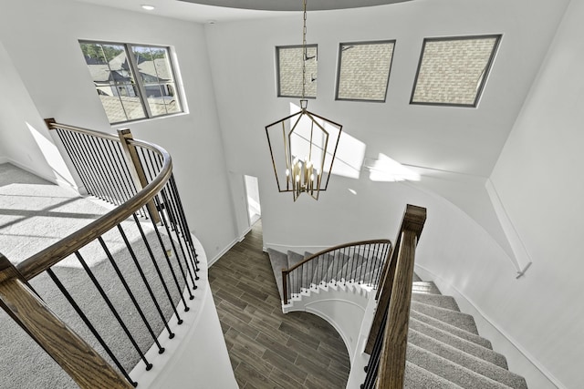 stairs featuring a chandelier, wood finished floors, and baseboards