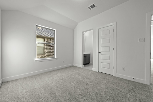 unfurnished bedroom featuring light carpet, visible vents, baseboards, and vaulted ceiling