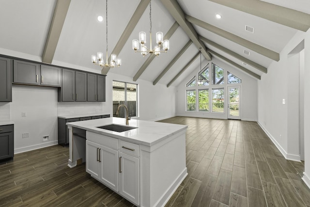 kitchen featuring beamed ceiling, a sink, open floor plan, a notable chandelier, and dark wood-style floors