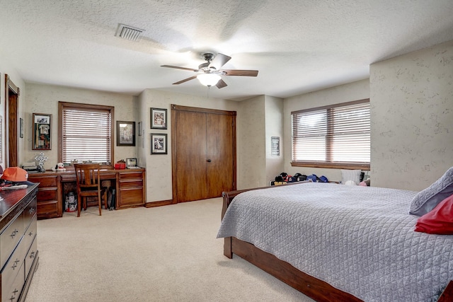 carpeted bedroom with a textured ceiling, multiple windows, and ceiling fan