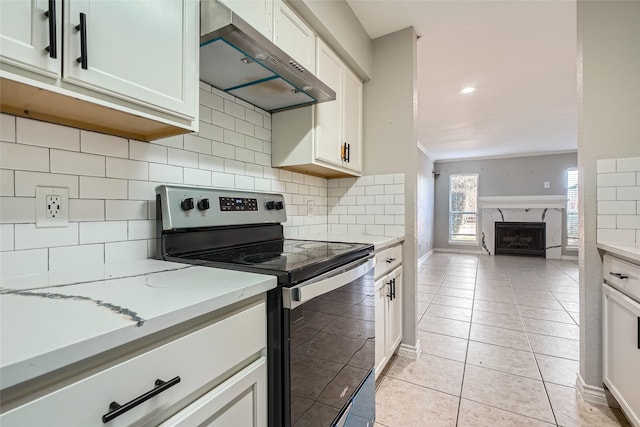 kitchen with white cabinets, stainless steel electric range oven, tasteful backsplash, light tile patterned flooring, and light stone counters